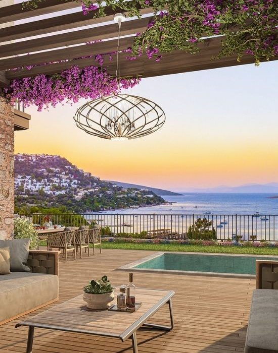 Bodrum'da Ege Denizi manzarasına karşı, özel havuzlu ve begonvillerle süslü lüks villa terasında gün batımı keyfi.