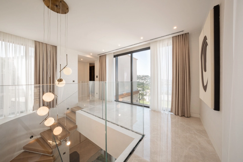 Gift Hebil villasında üst kattan merdiven ve geniş cam detayının görüldüğü modern iç mekân.